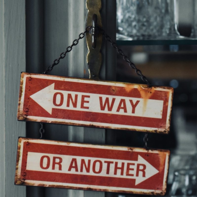 two red and white signs hanging from a metal pole